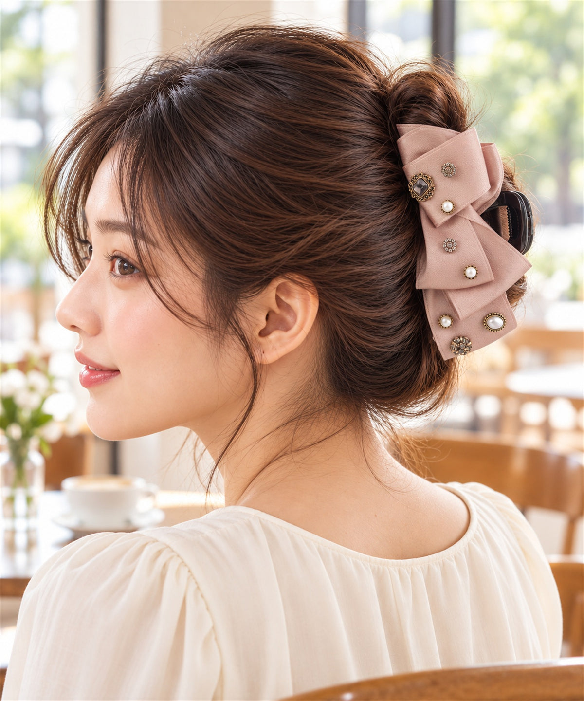 Nilda バンスクリップ ピンク 昼のカフェでの横顔の着用イメージ